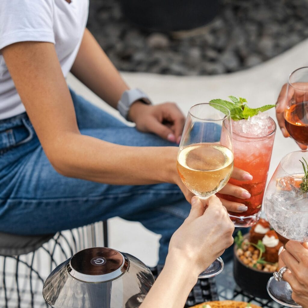 Lifestyle Group of friends enjoying drinks and food outdoors in Dubai, capturing a moment of leisure and togetherness.